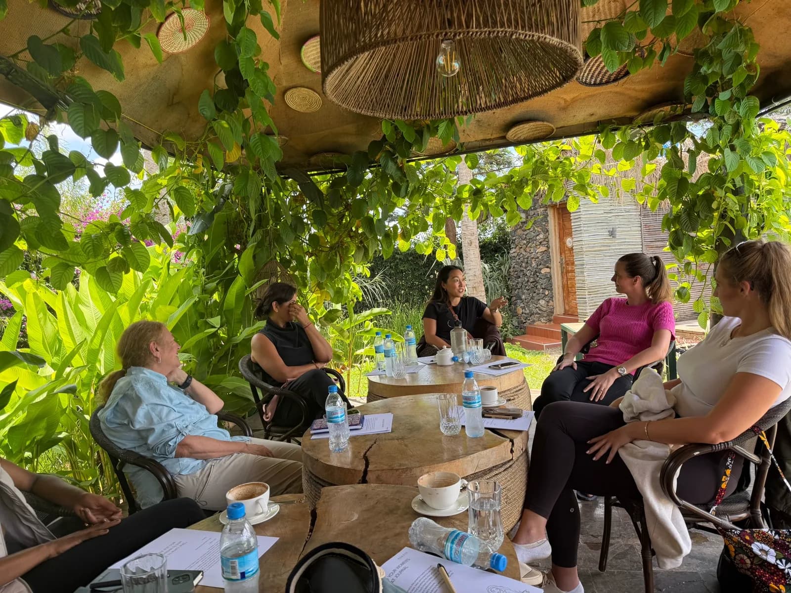 Women leaders in an intimate coaching circle under a leafy pergola at the Kilimanjaro retreat